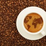 white-cup-espresso-with-world-map-froth-background-roasted-coffee-beans_273651-321